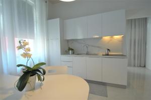 a kitchen with white cabinets and a vase with a plant at Althamer Palace Apartments in Arco