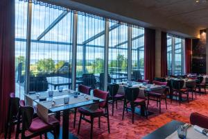 un ristorante con tavoli, sedie e ampie finestre di Spa Tervise Paradiis a Pärnu