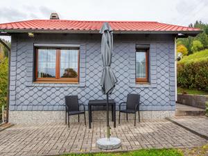 une maison bleue avec trois chaises et un parasol dans l'établissement Holiday home in Thuringia near the lake, à Langenbach