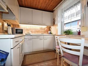 cocina con armarios blancos, mesa y sillas en Apartment in Thuringian Forest with garden en Oberweißbach