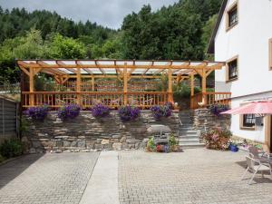 a patio with a stone wall and a wooden pergola at Beautiful Apartment in Merschbach with Garden in Merschbach