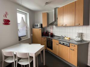 een keuken met houten kasten en een witte tafel en stoelen bij Geräumiges Apartment mit Balkon in Willingen in Willingen