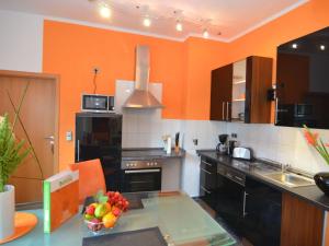 eine Küche mit orangefarbenen Wänden und einem Tisch mit einer Schale Obst in der Unterkunft Romantic apartment with courtyard in Langewiesen