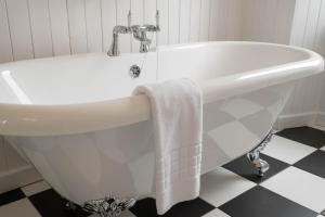 a white bath tub in a bathroom with a sink at Summer Isles Hotel in Achiltibuie