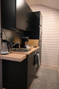 uma cozinha com armários pretos e um lavatório em Willa Rauha G em Lumijoki