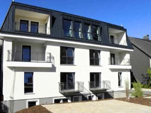 ヴィンターベルクにあるCozy Apartment In Winterberg Sauerland With Balconyの白い建物(バルコニー付)と黒い屋根