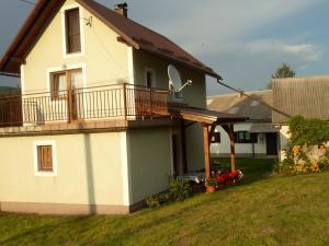 a white house with a balcony and a yard at Vacation home Kuća za Odmor in Krasno Polje