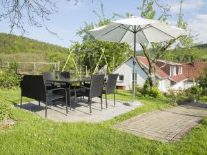 a table and chairs with an umbrella in a yard at Holiday home near forest in Fischbach in Emsetal