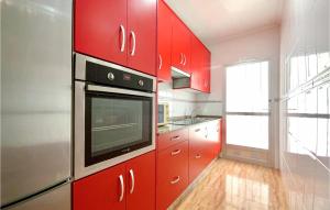 cocina con armarios rojos y microondas en 2 Bedroom Amazing Home In Los Alczares, en Los Alcázares