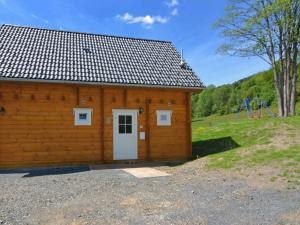 un edificio de madera con puerta blanca y parque infantil en Home in Wissinghausen with Private Sauna, en Medebach