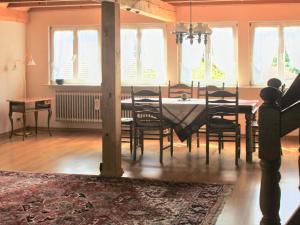 uma sala de jantar com mesa, cadeiras e janelas em Beautiful apartment near the lake em Herrischried