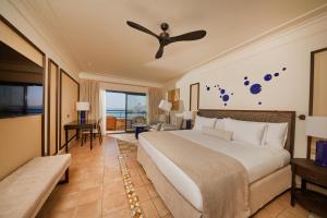 a hotel room with a bed, chair, and nightstand at Secrets Bahía Real Resort & Spa Adults only in Corralejo