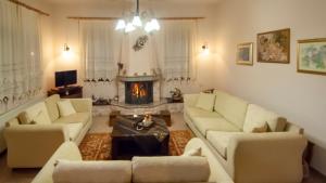 ein Wohnzimmer mit weißen Sofas und einem Kamin in der Unterkunft Elati Electra's Cozy House in Elati, Trikala