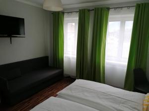 1 dormitorio con cortinas verdes, 1 cama y 1 sofá en Gästehaus Ruinenblick, en Spitz