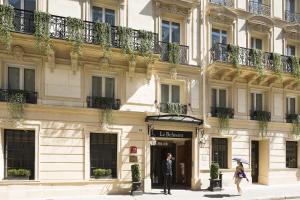 un uomo in piedi fuori da un edificio con un ombrello di Le Belmont Paris a Parigi