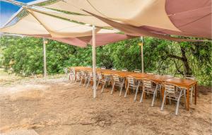 a long table and chairs under a large umbrella at Awesome Home In Ardenya With Wifi in Ardenya