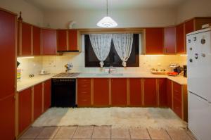 eine Küche mit roten Schränken, einem Waschbecken und einem Fenster in der Unterkunft Elati Electra's Cozy House in Elati, Trikala