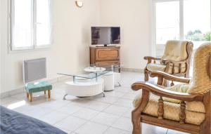 a living room with a tv and a chair and a table at Gorgeous Home In St Marcouf De L'isle in Saint-Marcouf