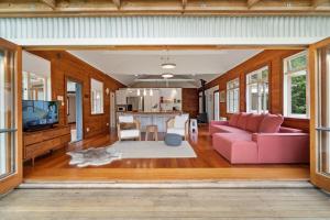 a living room with a pink couch and a tv at Stillhaven - Kerikeri Riverside Retreat in Kerikeri