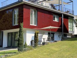 a red and white house with a table and an umbrella at Ferienwohnung Rack in Wangen im Allgäu