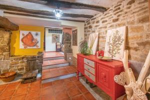 sala de estar con cómoda roja y pared de piedra en Casa rural Ezkonberri, en Unzué