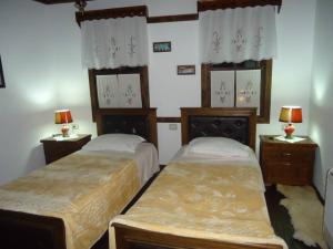 a bedroom with two beds and two tables and two lamps at Hotel Klea in Berat