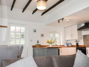 a kitchen and living room with white cabinets and a couch at Heligan Cottage in St Austell