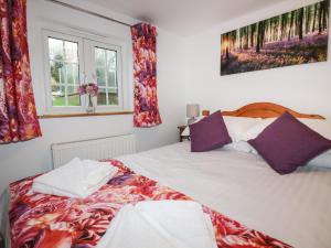 a bedroom with a large white bed with purple pillows at Heligan Cottage in St Austell