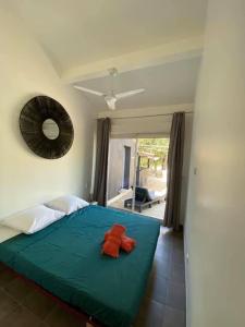 a bedroom with a green bed with two red pillows on it at LA MANOSC in Grimaud