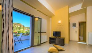 um quarto com uma grande porta de vidro deslizante e uma televisão em Nostalgia Apartments Zante em Zakynthos