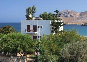 a white house on a hill with trees and water at Mealos Apartments in Skiros