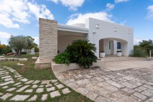 una casa blanca con un camino de piedra en el patio en Villa LUCI' in Puglia, vicina alla VALLE DI ITRIA, en Mottola