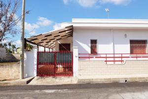 una casa bianca con un cancello rosso di Villetta Greta a Torre Lapillo