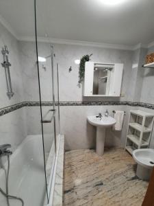 uma casa de banho com uma banheira, um lavatório e um chuveiro em Piso céntrico en O Grove em O Grove