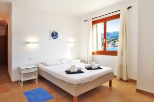a white bedroom with a bed and a window at Es Faro House by Slow Villas in Port de Soller