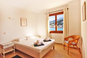 um quarto com uma cama, uma cadeira e uma janela em Es Faro House by Slow Villas em Port de Sóller
