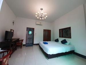 um quarto com uma cama, uma televisão e um lustre em Chaing Dao Koko Home / โกโก้ โฮม เชียงดาว em Chiang Dao