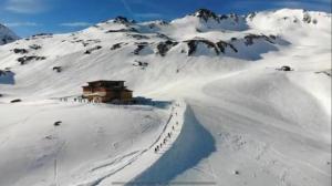 a snow covered mountain with a building in the distance w obiekcie Wallackhaus hütte w mieście Untertauern