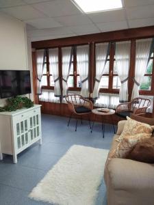 a living room with a couch and chairs and windows at Apartamento Valle del Güeña in Benia de Onís