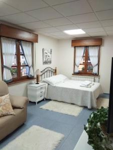 a bedroom with a bed and a couch and windows at Apartamento Valle del Güeña in Benia de Onís