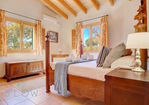 a bedroom with a bed and a table and windows at Villa Cas Frares by Slow Villas in Santa Maria del Camí