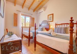 een slaapkamer met 2 bedden en een raam bij Villa Cas Frares by Slow Villas in Santa Maria del Camí