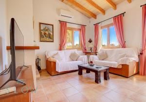 a living room with two white couches and a tv at Villa Cas Frares by Slow Villas in Santa Maria del Camí