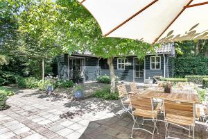 a patio with a table and chairs under an umbrella at B&B Van Gogh Cottage in Nuenen