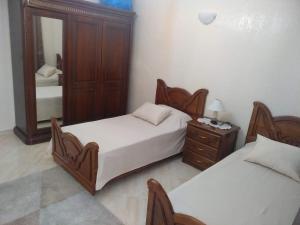 a bedroom with two beds and a dresser and a mirror at Appartement Bio Meknes Hamria in Meknès