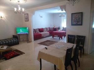 un soggiorno con tavolo e divano rosso di Appartement Bio Meknes Hamria a Meknès