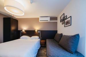 pokój hotelowy z łóżkiem i kanapą w obiekcie Sure Hotel by Best Western Châteauroux w mieście Le Poinçonnet