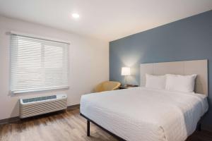 a bedroom with a white bed and a window at WoodSpring Suites Tampa Airport North Veterans Expressway in Tampa