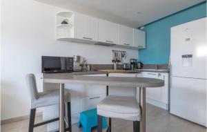 a kitchen with white cabinets and a table and chairs at Lovely Apartment In La Grande-Motte in La Grande-Motte