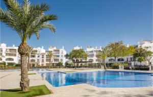 a palm tree in front of a swimming pool with buildings at 2 Bedroom Nice Apartment In Roldán in Los Tomases +15 photos
